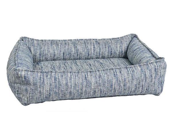 The Portofino urban lounger dog bed from bowsers. It's light blue with very thin upholstered white and gray stripes. It's a rectangle with four padded bolsters